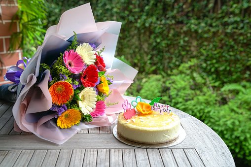Bouquet of gerbera daisy flowers and cheese cake as birthday present or gift